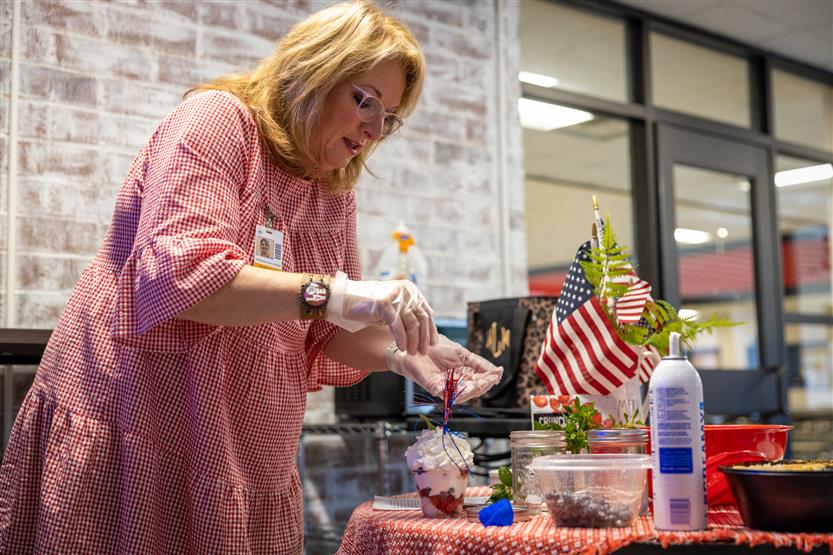 A teacher wearing pink demonstrates how to make a parfait
